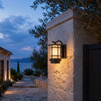 Craftsman wall lantern on a stone pillar with a sea view and olive tree behind