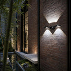Two wave wall lights on dark brick beside glass doors and bamboo planting