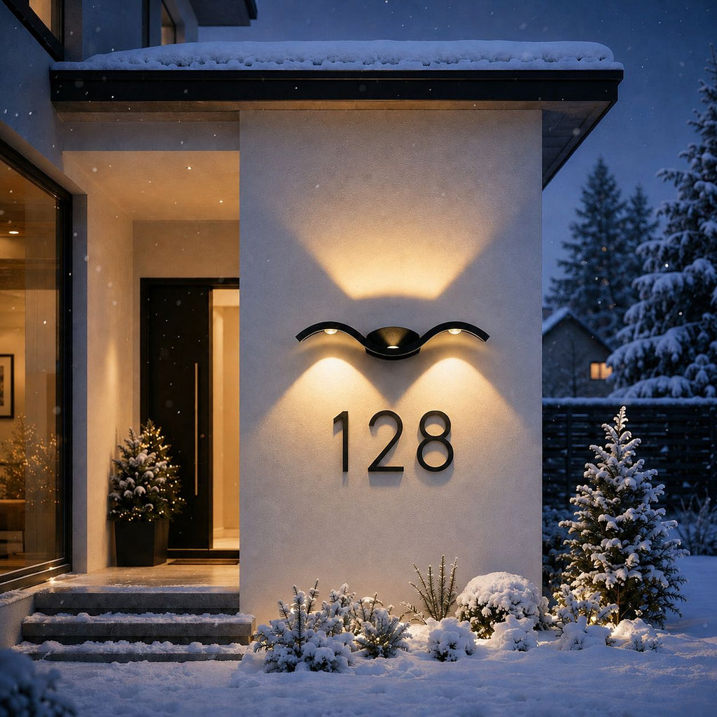 Wave wall light above a house number on a snowy entrance wall in winter
