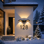 Wave wall light above a house number on a snowy entrance wall in winter