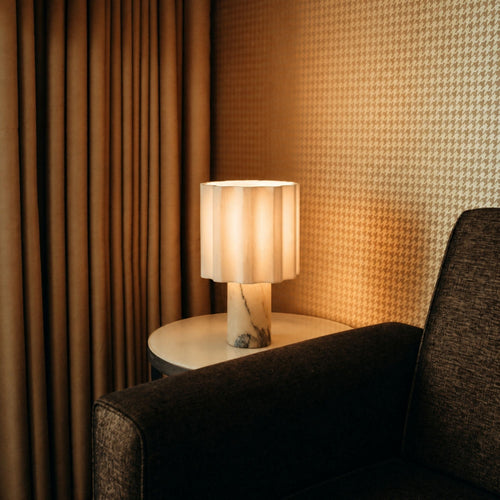 Portable Calacatta marble table lamp with linen shade on side table creating warm ambient lighting