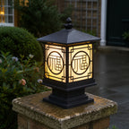 Tall fretwork lantern post cap lit on a mossy stone pier at dusk