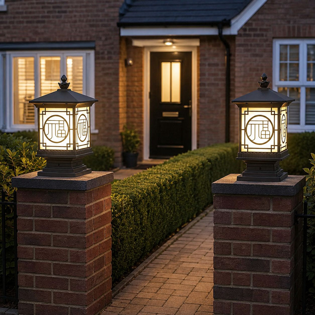 Two tall lantern post caps on brick piers beside a lit front door