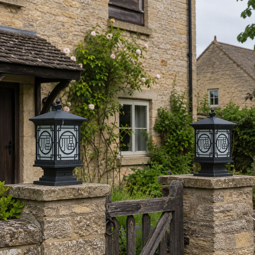 Two tall lantern post caps on stone piers at a cottage gate