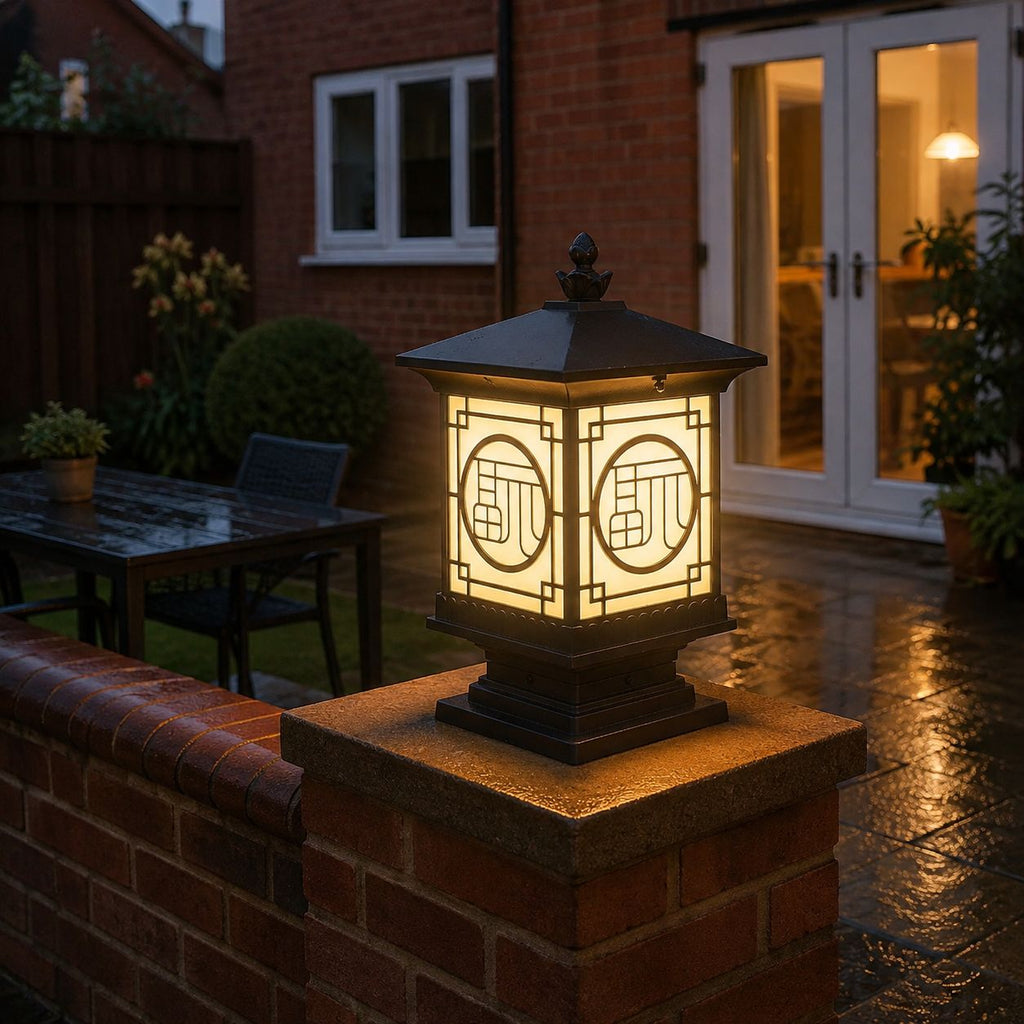 Tall lantern post cap on a brick pier beside a lit patio and French doors