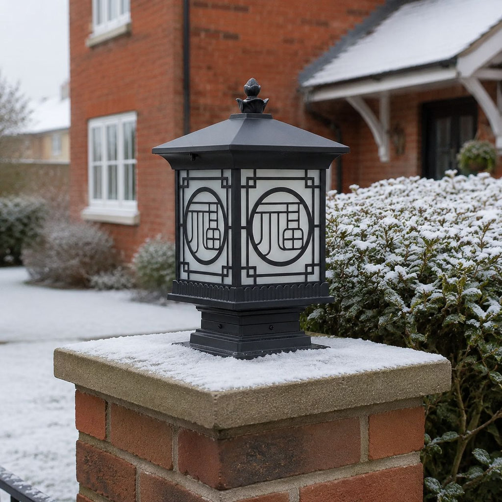 Tall lantern post cap unlit on a snow-covered brick pier