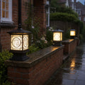 Three tall lantern post caps along a wet brick garden wall at night