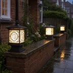 Three tall lantern post caps along a wet brick garden wall at night