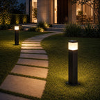 Two bollard lights lighting a stepping stone path across a lawn