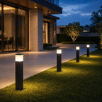 Four slim bollard lights edging a lawn beside a modern house at blue hour