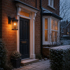 Caged glass wall lantern beside a dark front door with snow on the hedging