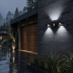 Black wave wall light in cool white on dark stone beside a garage door