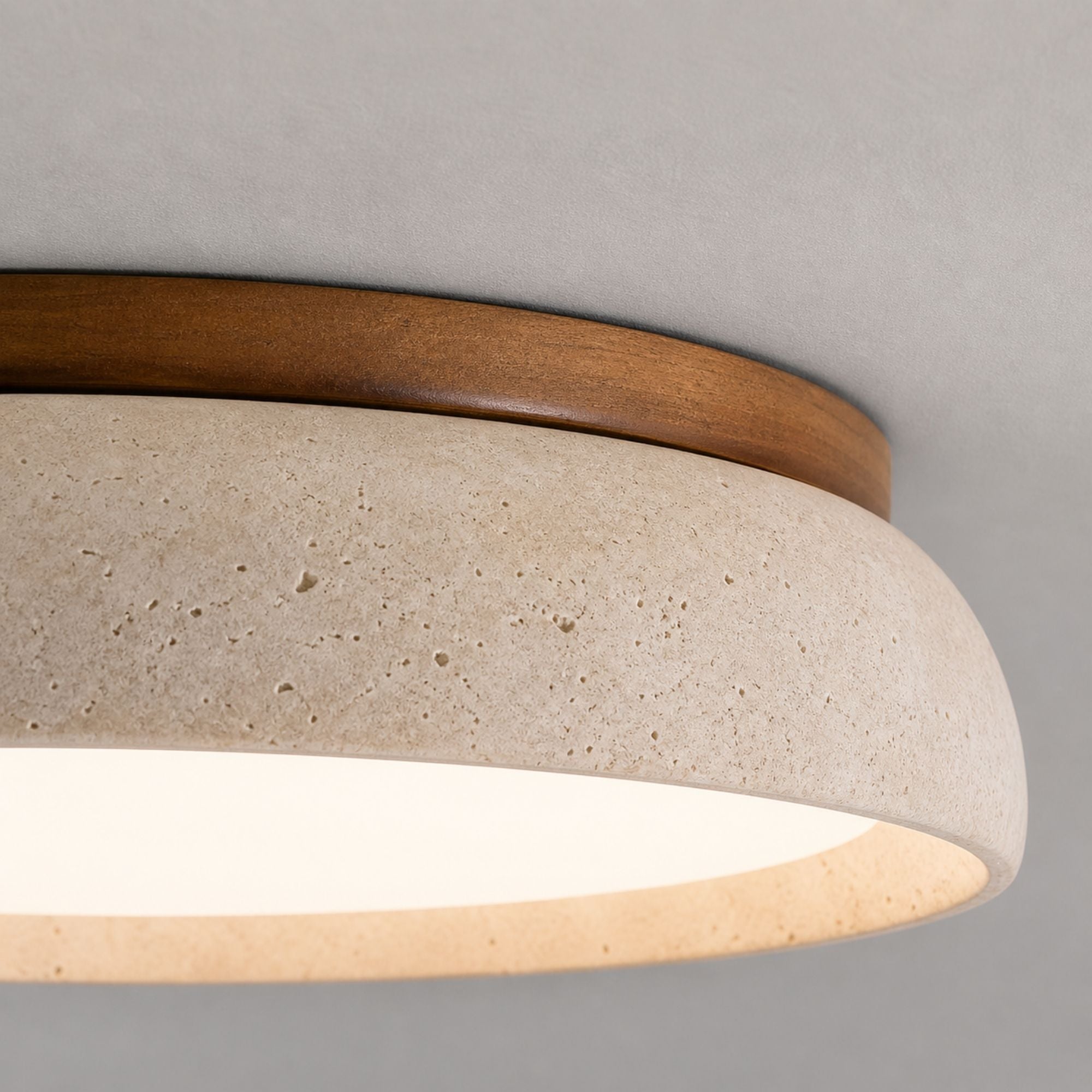 TravertineGlow ceiling light close-up showing beige travertine texture with natural pores and warm wood trim detail