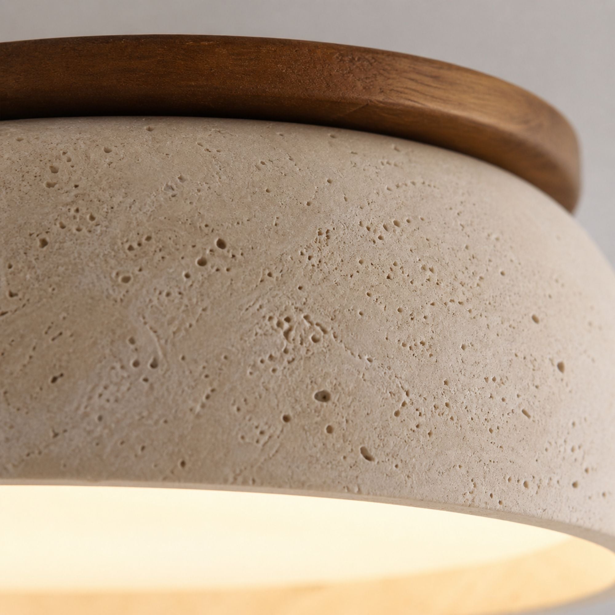 Macro close-up of beige travertine ceiling light surface highlighting natural stone pores and warm LED glow