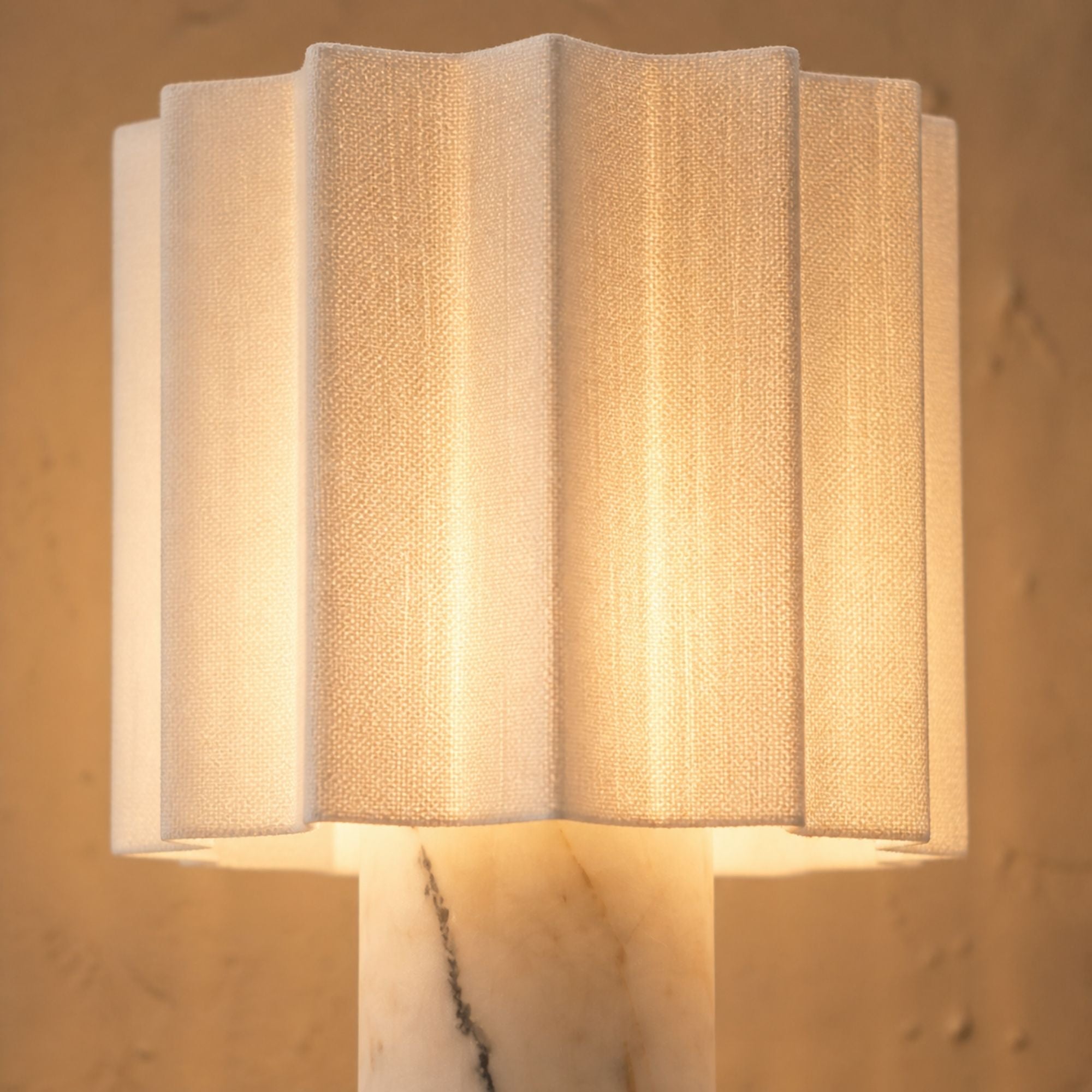 Close-up of Calacatta marble table lamp with linen shade showing warm ambient light diffusion