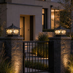 Pair of traditional pillar lanterns on stone gate posts flanking an iron gate at dusk