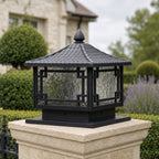 Daylight view of the coffee gold lantern on a white stone pillar cap beside clipped hedging