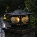 Traditional pillar lantern lit in heavy rain, water running over the frosted glass