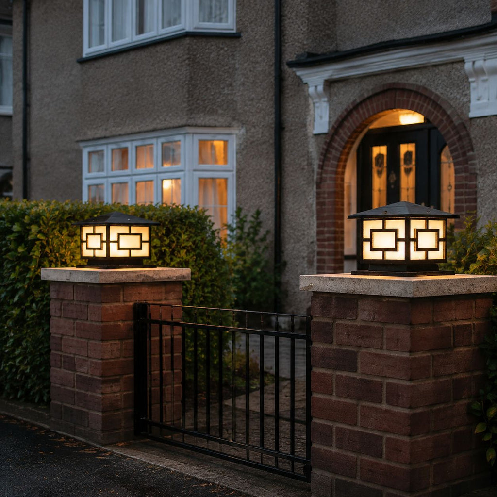 Two pagoda pillar lights on brick piers flanking an iron gate at dusk
