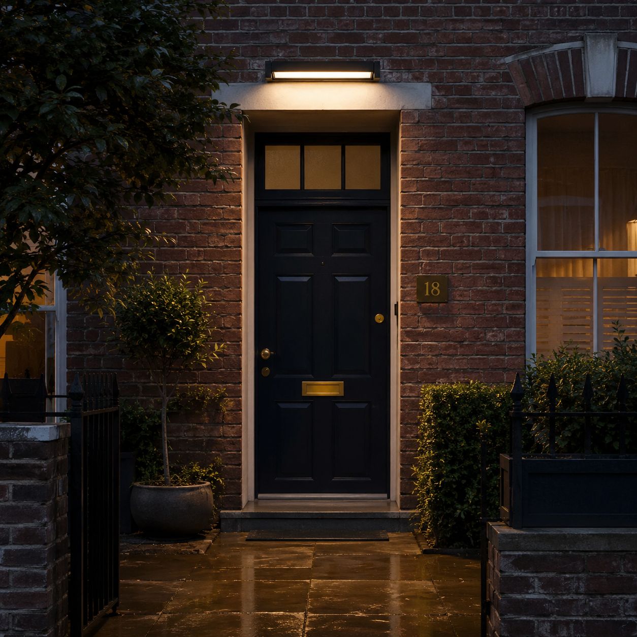 Rotating linear wall light above a dark front door on wet paving