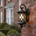 Lattice wall lantern on red brick beside clipped topiary