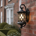 Lattice wall lantern on red brick beside clipped topiary