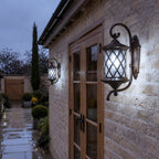 Two lattice wall lanterns on brick beside timber doors after rain