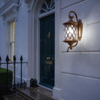 Lattice wall lantern on white render beside a teal door and iron railings