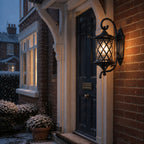 Lattice wall lantern on red brick beside a dark door during snowfall