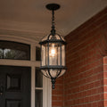 Domed pendant lantern in black hanging beside a dark front door on brick