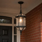 Domed pendant lantern in black hanging beside a dark front door on brick
