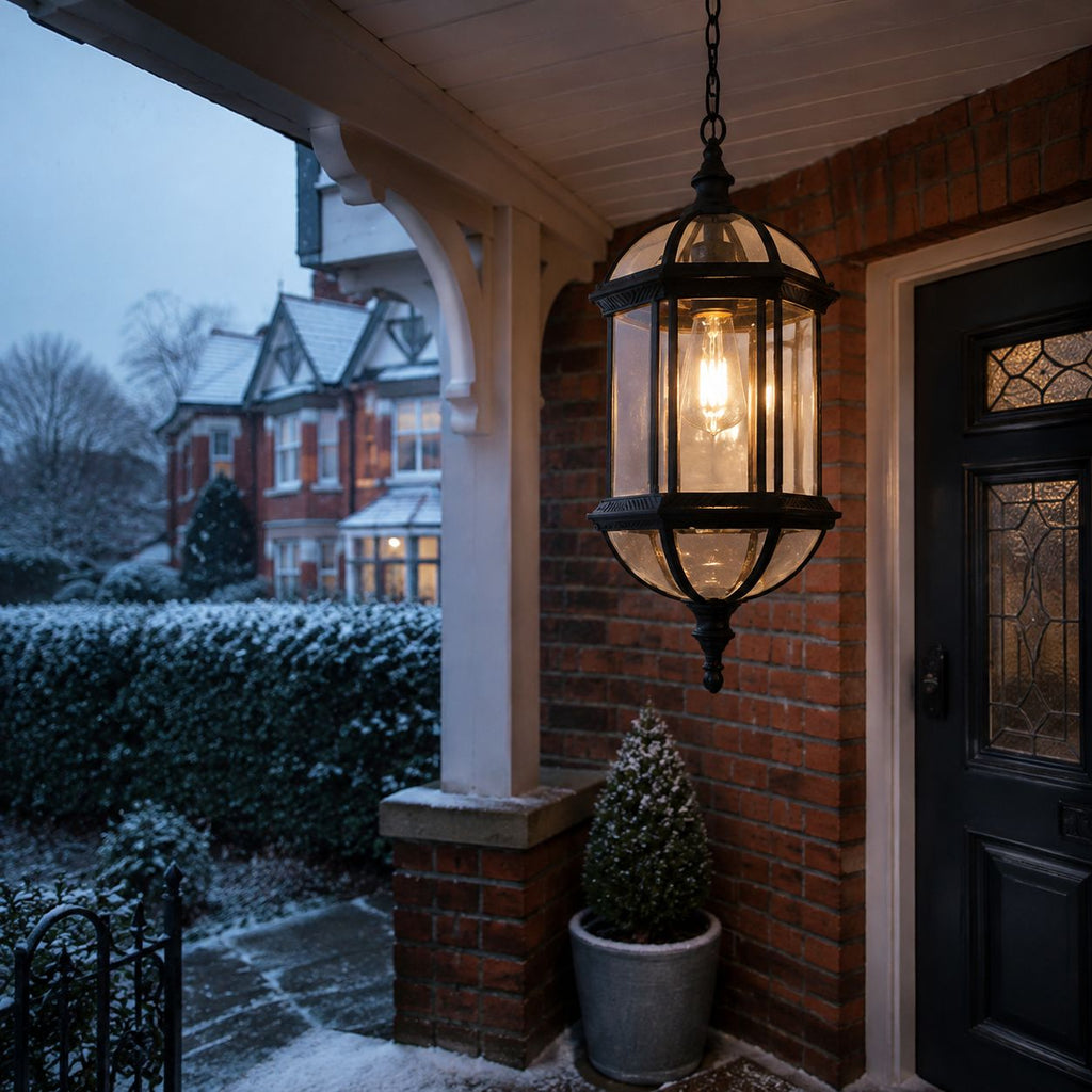 Domed pendant lantern under a brick porch with snow on the hedging