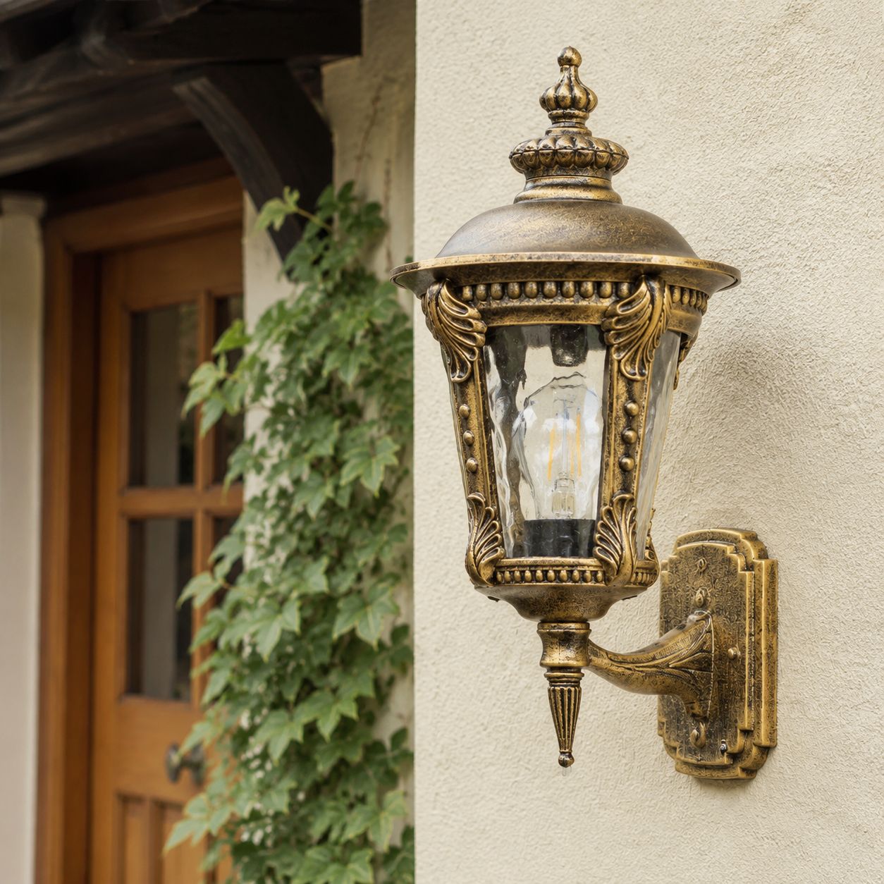 Bronze hammered glass wall lantern on cream render beside a timber door and ivy