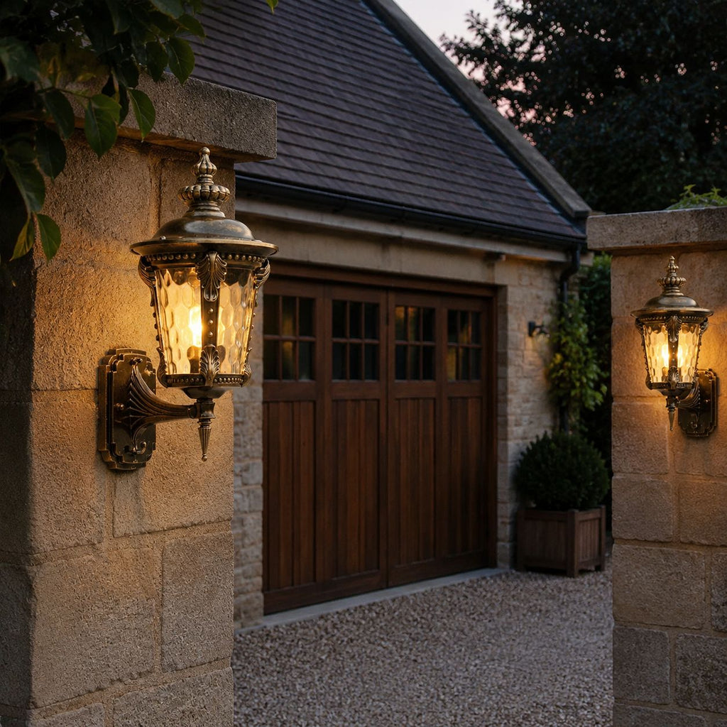 Two hammered glass wall lanterns lighting a stone garage entrance at dusk