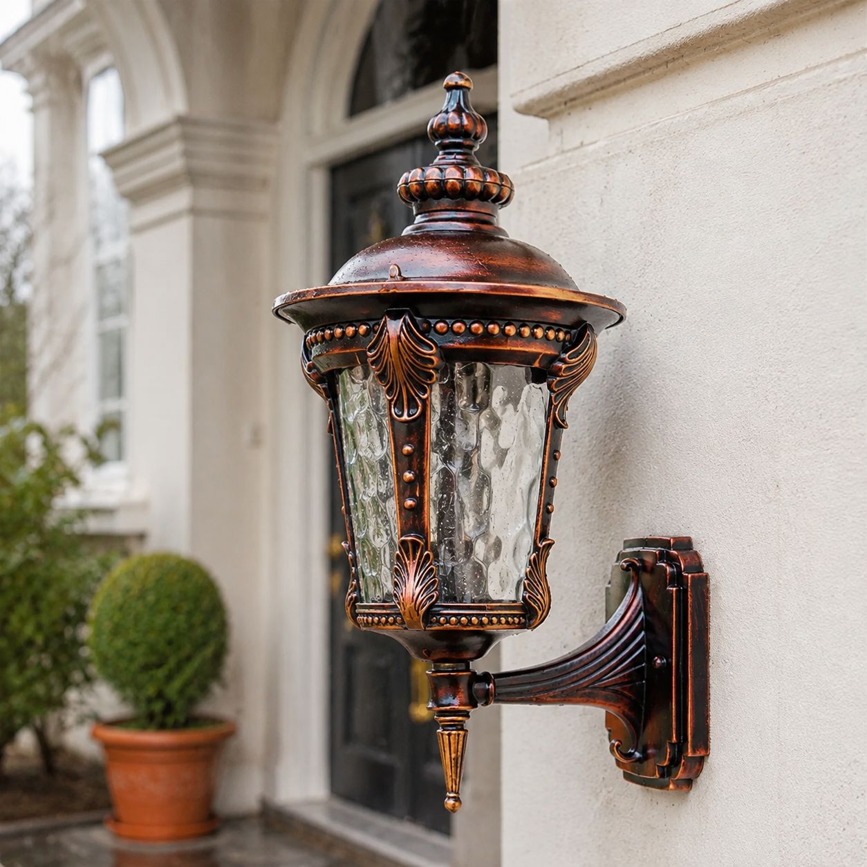 Red gold hammered glass wall lantern beside a glazed door and box topiary