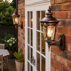 Two red gold hammered glass wall lanterns on brick either side of French doors