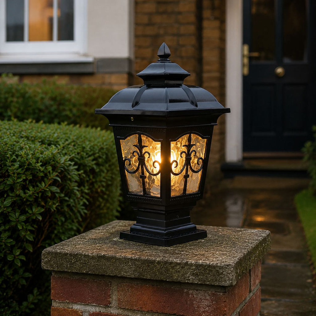 Black scrollwork pillar light on a stone pier beside a dark front door