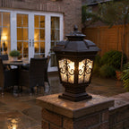 Scrollwork pillar light on a stone pier beside a patio and French doors