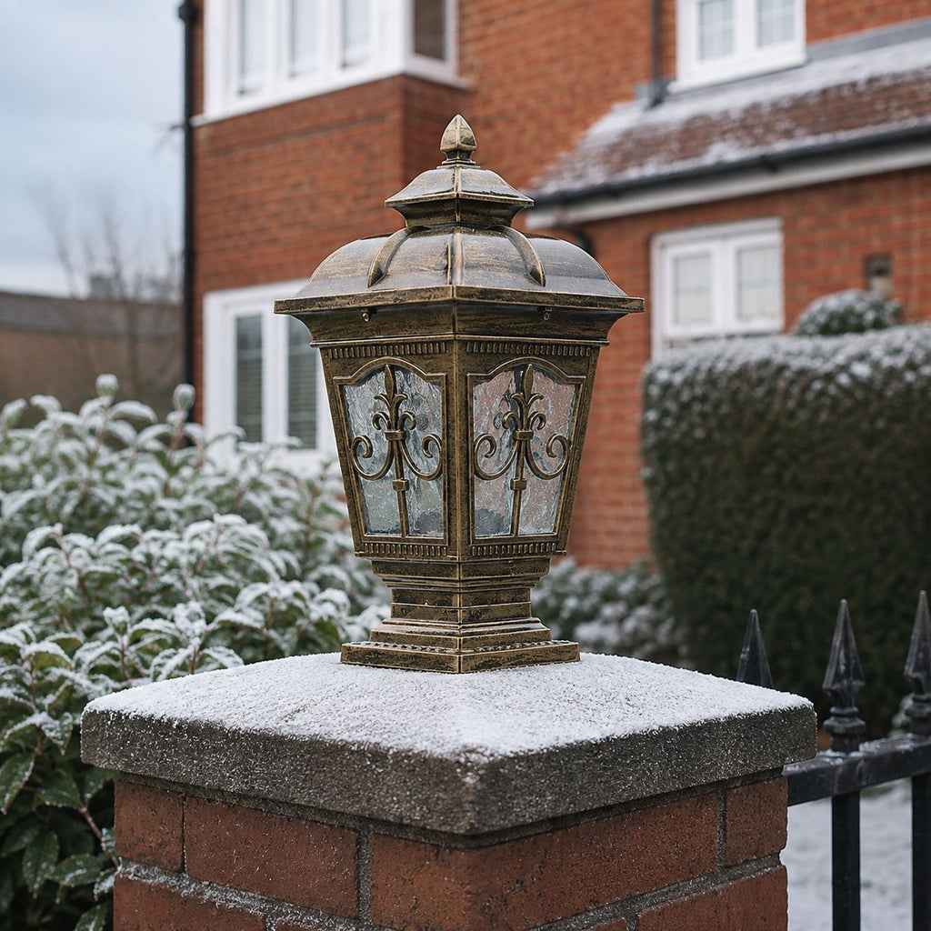 Bronze scrollwork pillar light on a snow-dusted brick pier