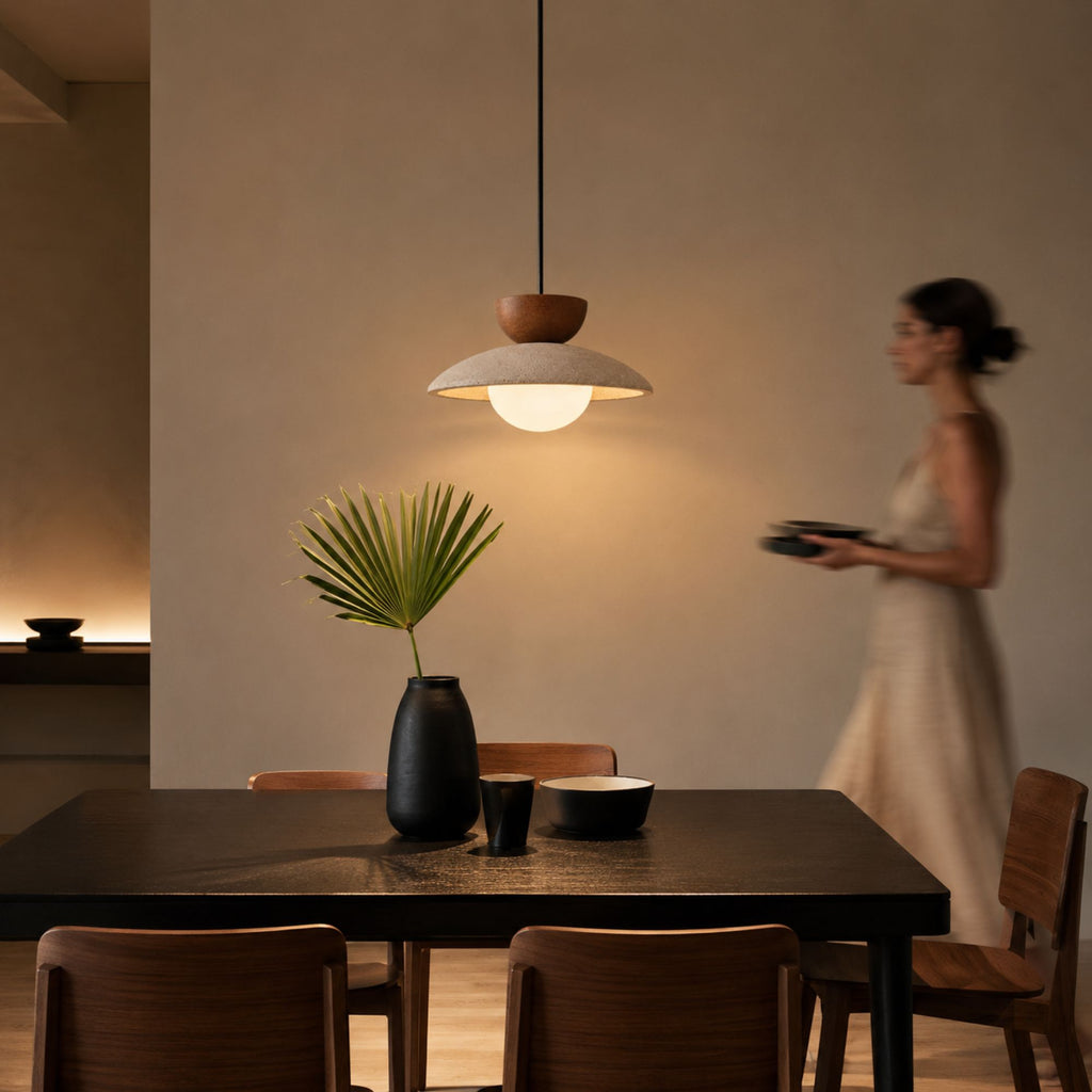 Elegant travertine ceiling pendant lamp styled in a modern neutral dining space with wooden furniture and cozy lighting