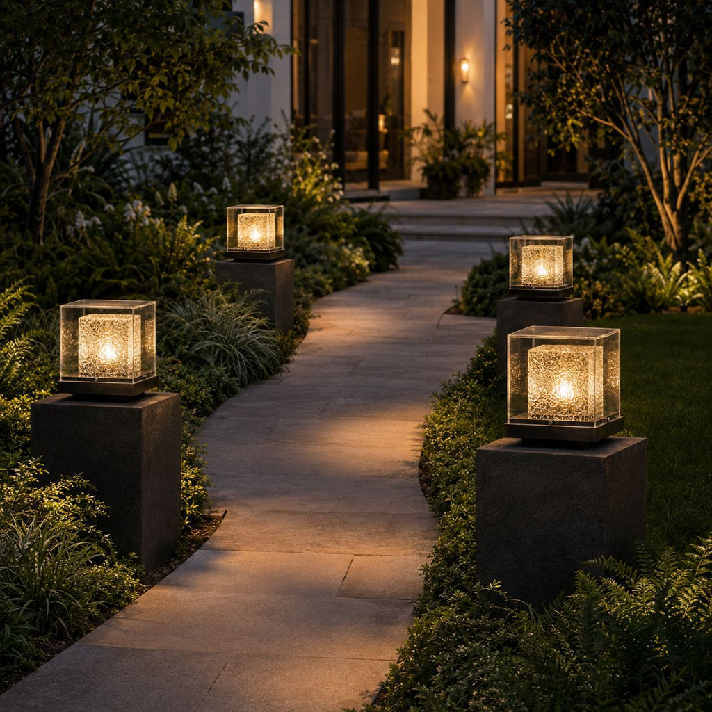 Four post cap lights on dark stone piers lining a garden path at dusk