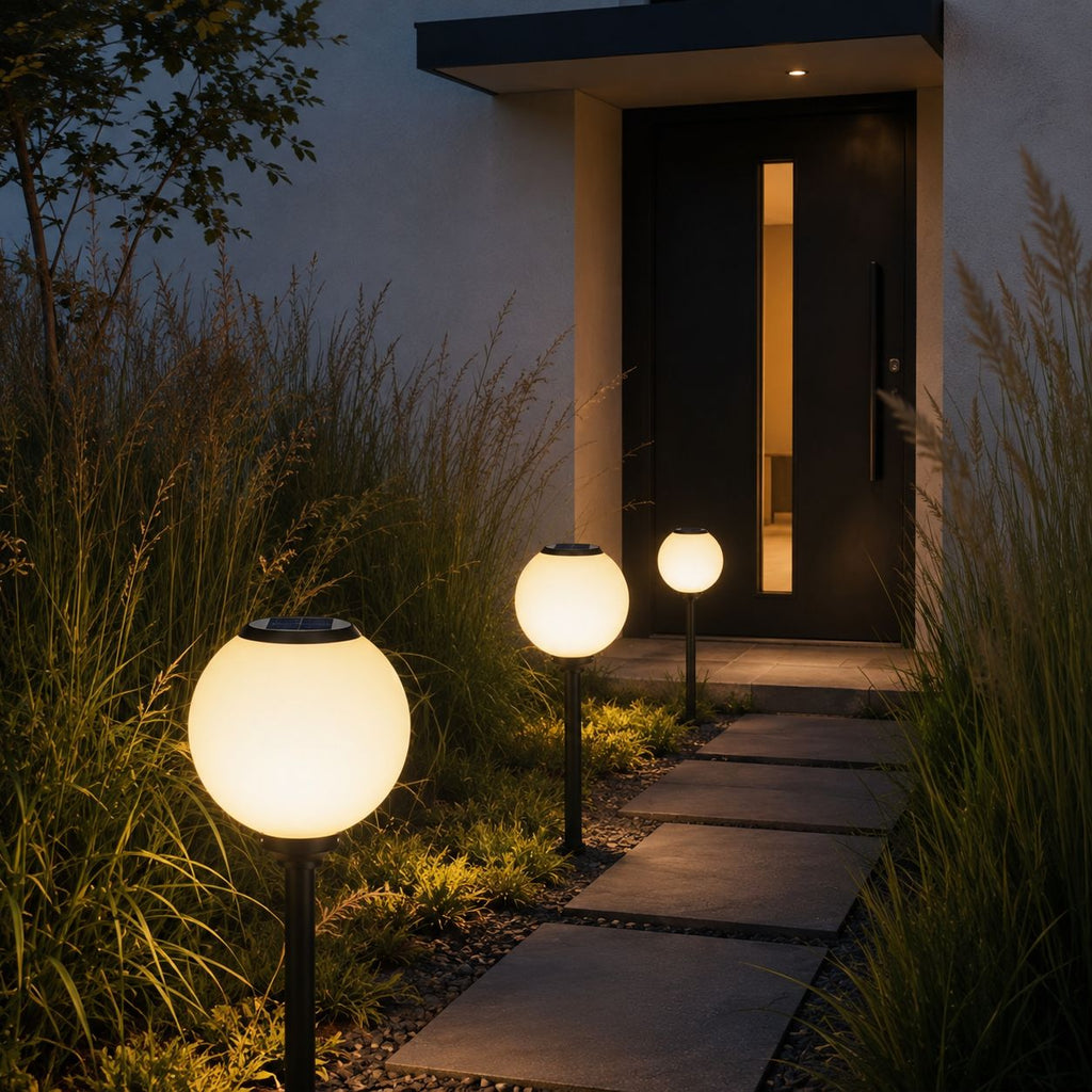Solar globe path lights along a garden path beside grasses at a modern entrance