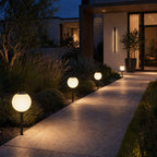 Solar globe lights lining a paved path with low planting at dusk