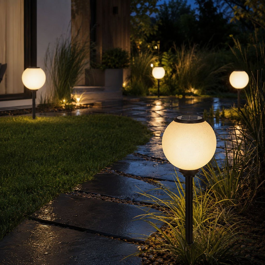 Solar globe path lights beside a lawn and stepping stones on wet paving