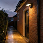 Angled LED wall light above a side door on brick at dusk