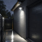 White angled LED wall light on dark cladding beside a garden gate at night