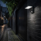 White angled LED wall light on dark brick in a cobbled alley