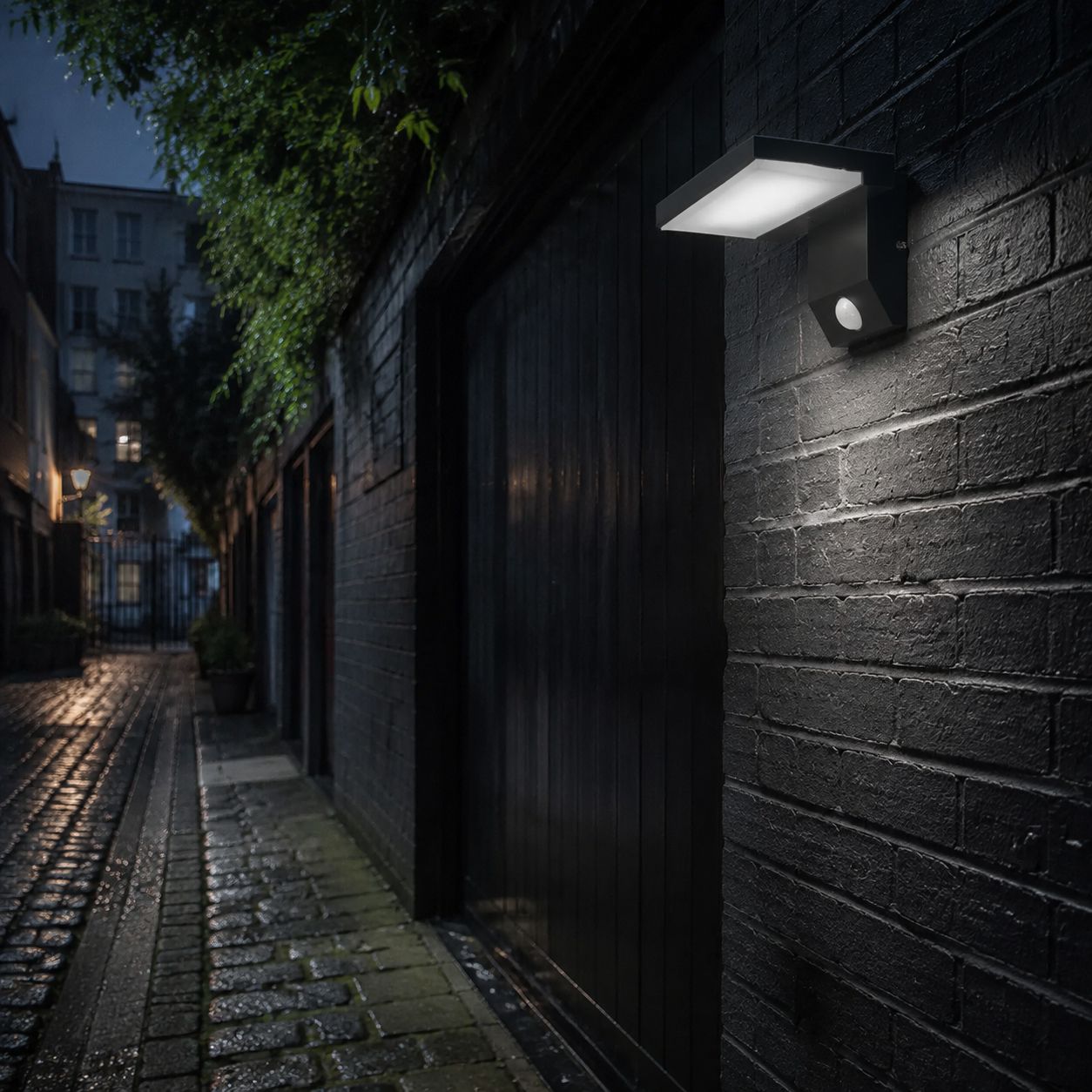White angled LED wall light on dark brick in a cobbled alley