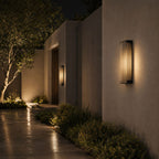 Fluted panel wall light on a rendered wall beside a lit path at dusk