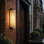 Fluted wall light on red brick beside a dark timber front door